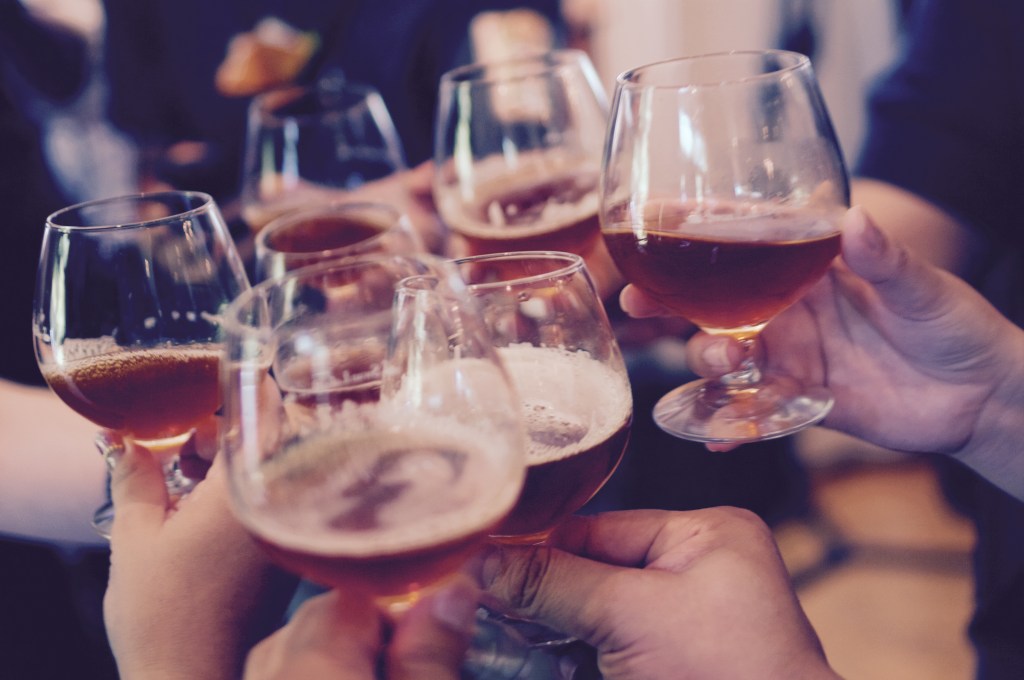 people raising their beer glasses to say cheers