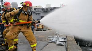 Feuerwehrleute spritzen mit Schlauch