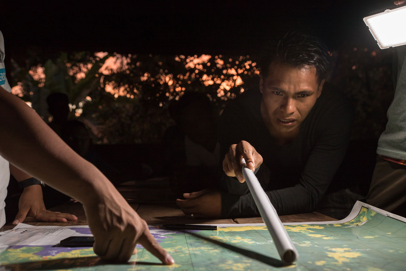 Hunched over a map in the village meeting hall, Elvis Cabezon points out nearby areas of deforestation he has marked with GPS coordinates.