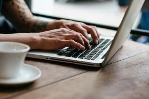 man sitting at a table and typing on a keyboard