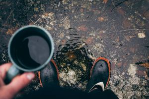 persona con café en mano bajo la lluvia