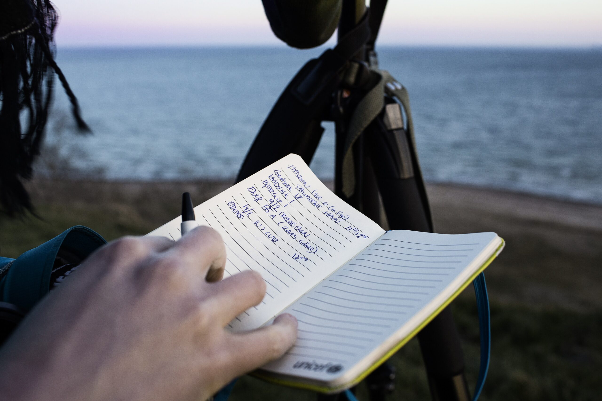 Sigrid Ilsøe skriver i en notesbog. Man kan se havet i baggrunden.