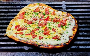 a homemade grilled carbonara-inspired pizza topped with mornay sauce and bacon on top of grill grates