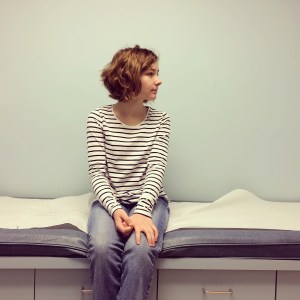 young woman in a doctor's office sitting on an exam table