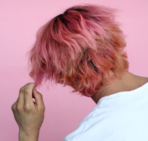 man pulling his pink hair