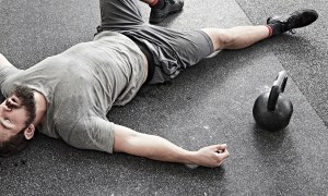 Man ligt op de grond naast een dumbell