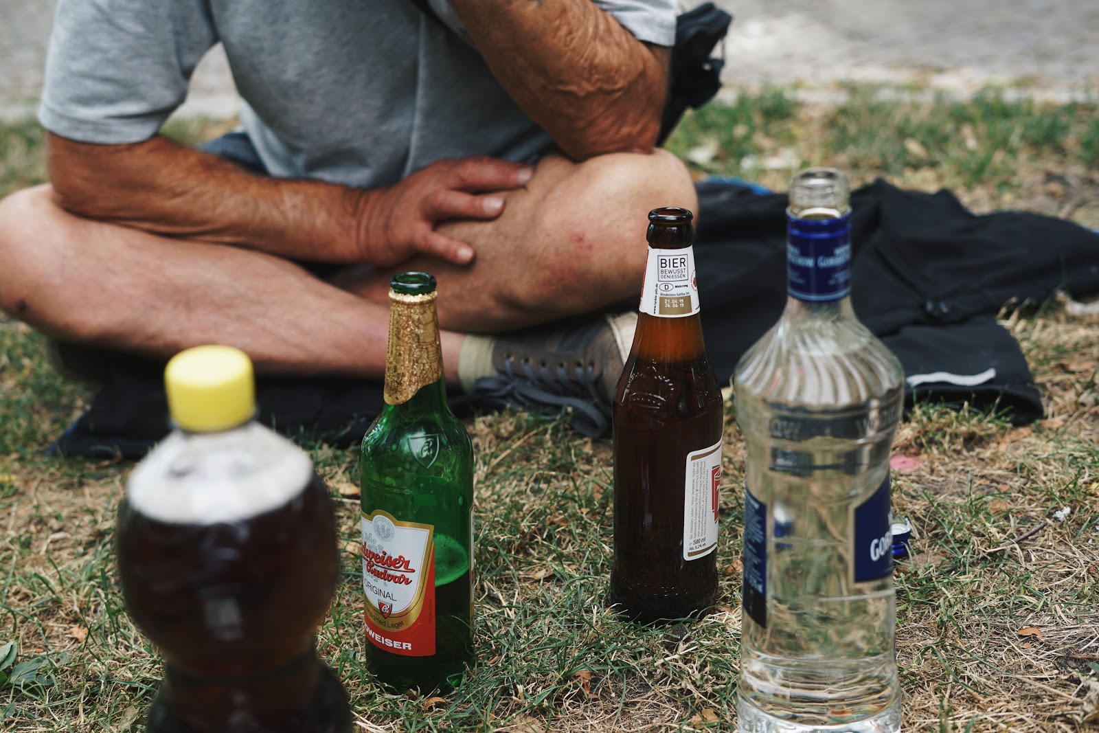 Ein Mann sitzt vor einer Auswahl an Getränken im Gras