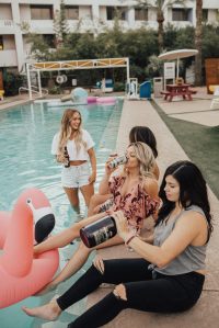 amigas a beber copos junto à piscina