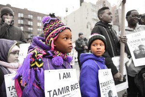 two black youth standing in a protest line wearing signs that say "I am tamir rice"