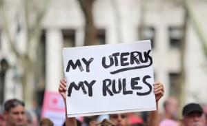 A protestor at an abortion rally holds a sign that says "My uterus my rules"