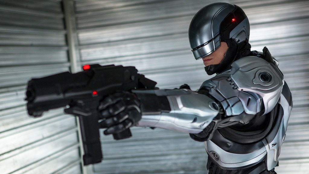 RoboCop mengacungkan pistol ke arah musuhnya.