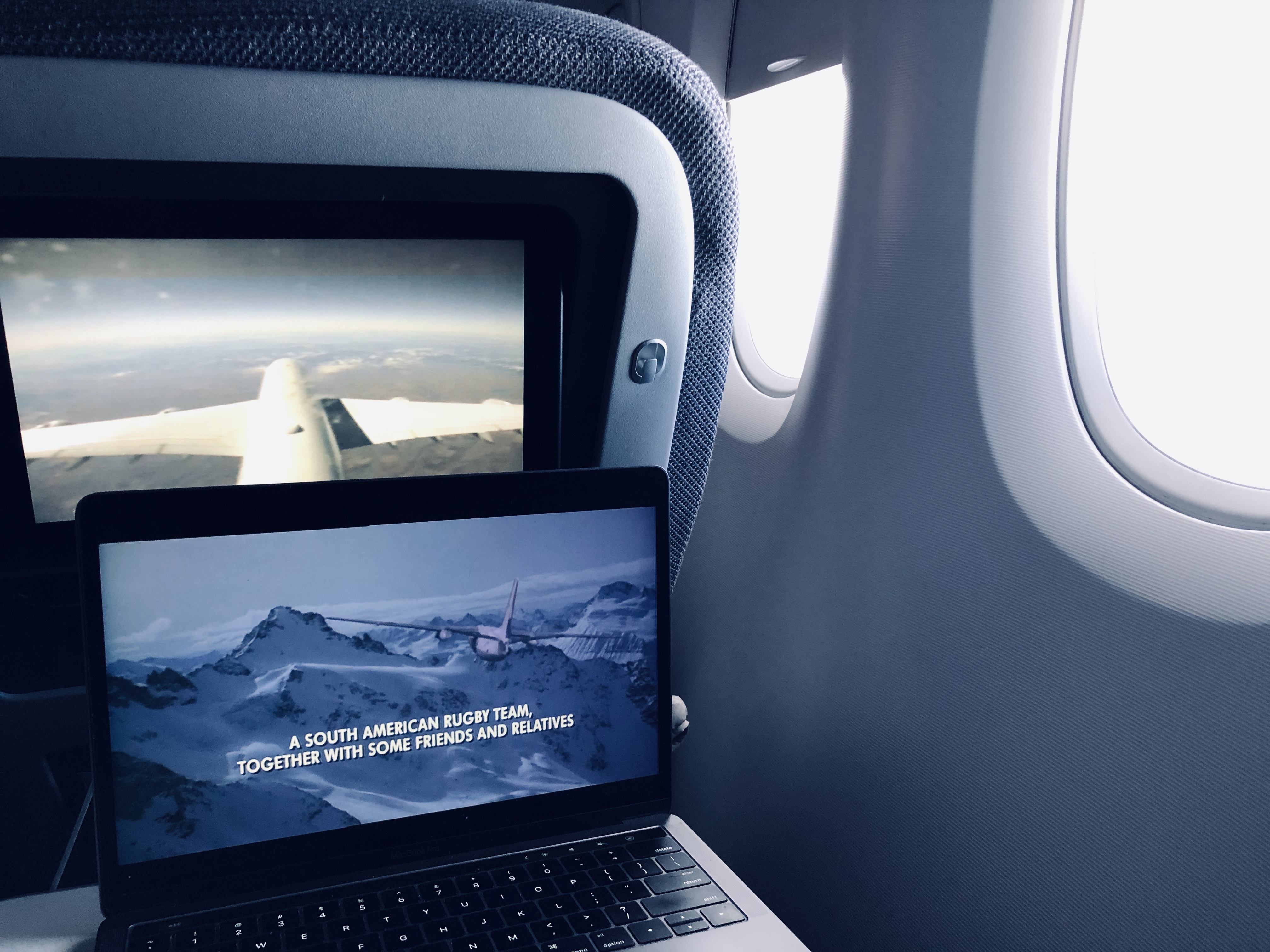 a laptop playing the movie Alive on an airplane tray table