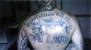 Michael Odisho's back tattoo of a submachine gun and crime scene