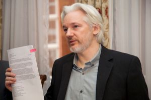 Julian Assange holding a document at a press conference in 2014