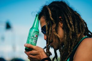 Ein junger Mann bei einer Demonstration für die Legalisierung von Marihuana, der gleichzeitig Alkohol und Gras konsumiert