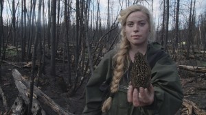 Woman holds morel mushroom in forest