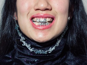 A woman with a grill over her teeth that has Chinese characters engraved in it.