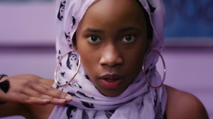 a young black girl in light purple hijab with gold hoop earrings.a