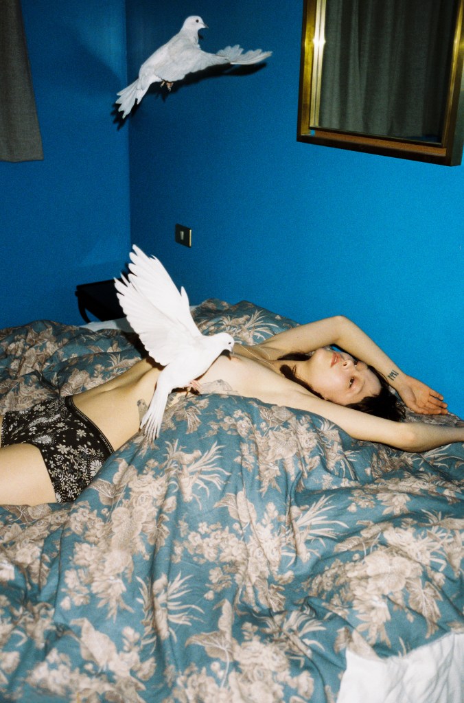 Chinese girl and white dove lying on a hotel bed.