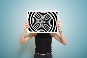 Young woman holding a photo of a black and white swirl pattern in front of her face