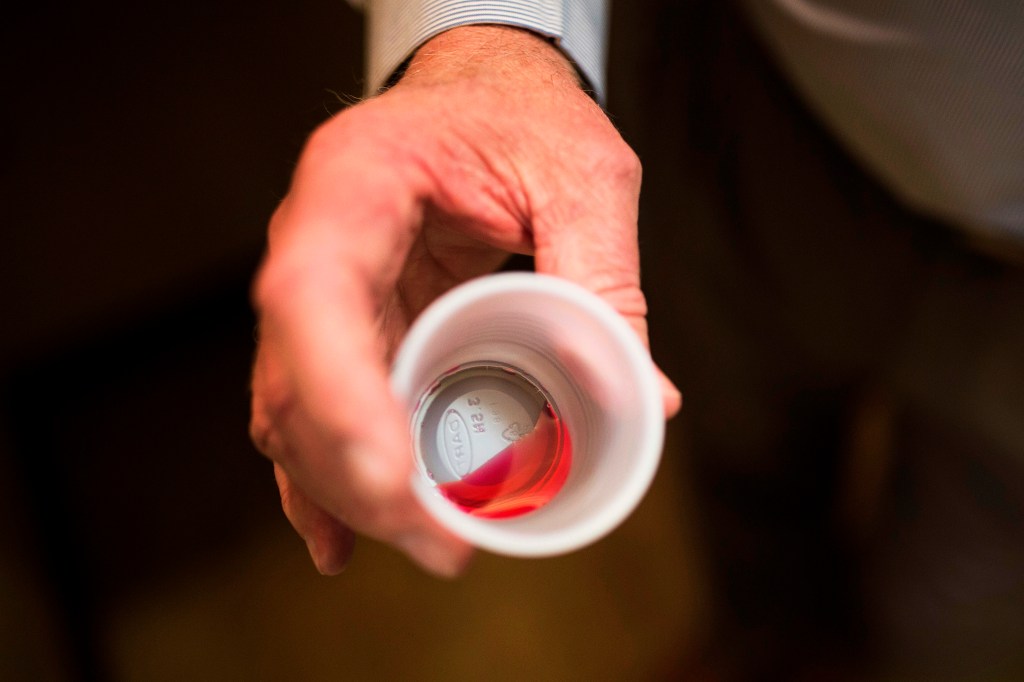 man holding a dose of methadone