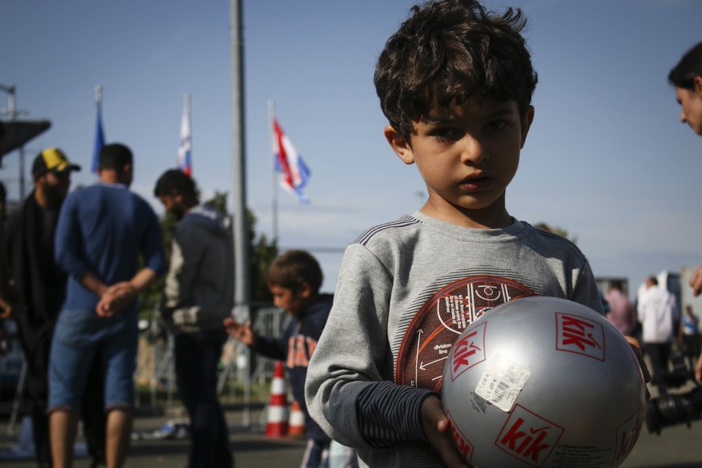 criança refugiada com uma bola de futebol nas mãos