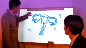 Zwei Männer schauen auf eine Tafel und fragen sich, was ein Uterus ist