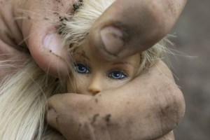 Mann zerdrückt den Kopf einer Plastikpuppe