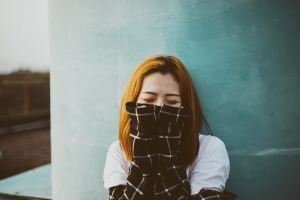 Bashful woman covering her face with her sleeves to represent the opposite of a narcissist: an echoist