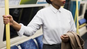 Schwarze Frau in Businesskleidung in der Londoner U-Bahn, Weiße Bluse