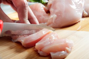 person cooking touching raw chicken slicing