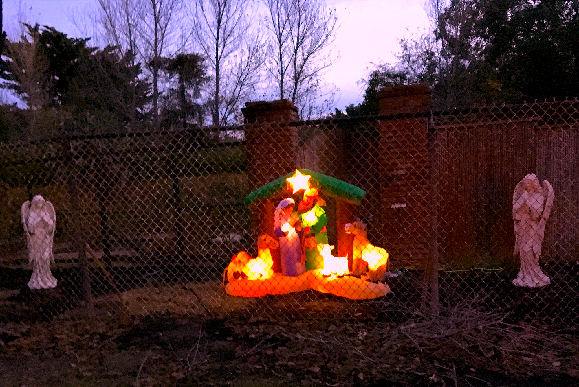 an inflatable nativity scene, flanked by angel statues