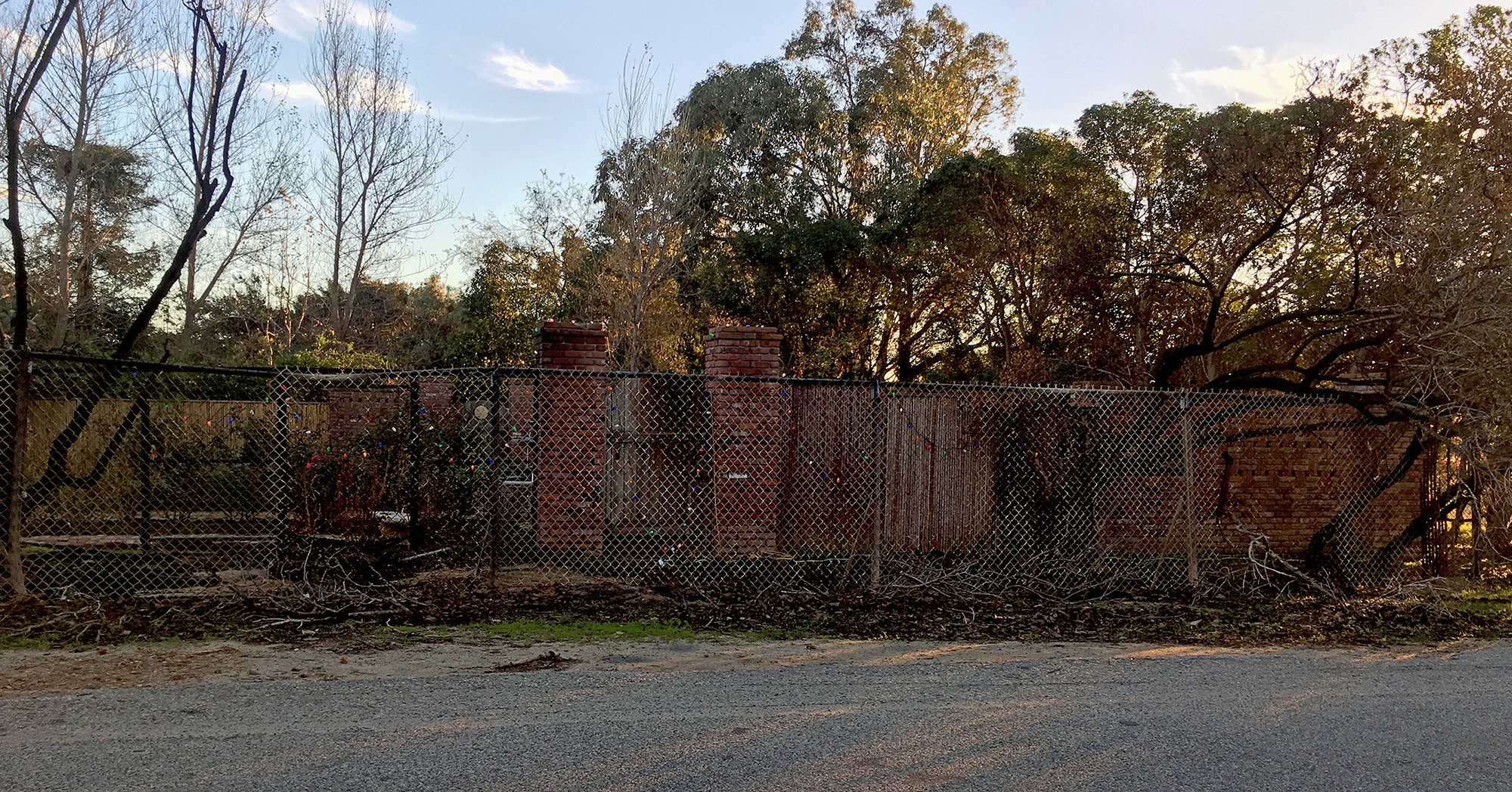 A hurricane fence in front of a brick wall