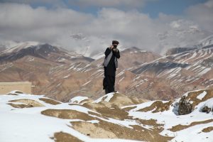 Niklas Schenck steht vor einer afghanischen Gebirgslandschaft und macht ein Foto