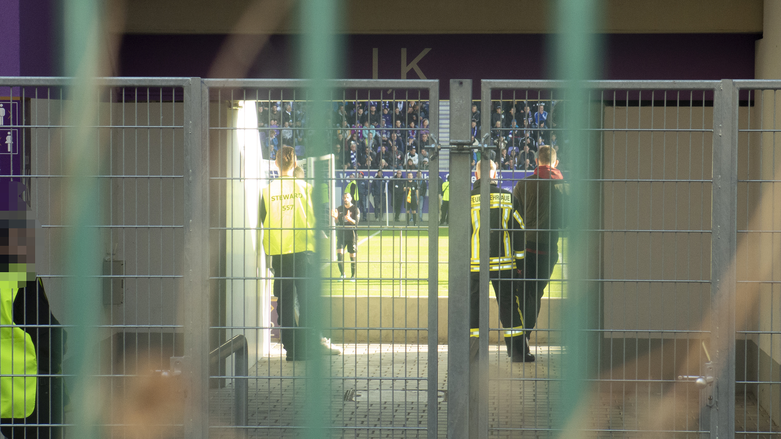 Sicherheitskräfte und Ordner hinter einem der Durchgänge im Fußballstadion