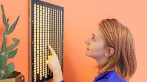 Simone Giertz stands before her latest invention, the Every Day Calendar, which she calls a "personal gold star system."