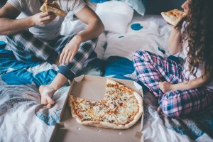 Man en vrouw zitten in bed pizza te eten