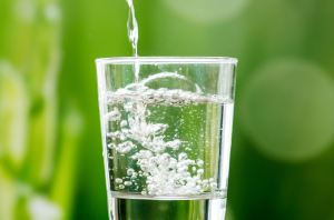 Water being poured into a glass in front of a green background