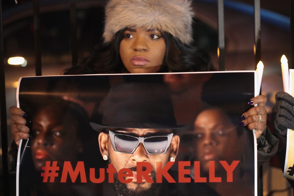 A protester holding a "mute R. Kelly" sign