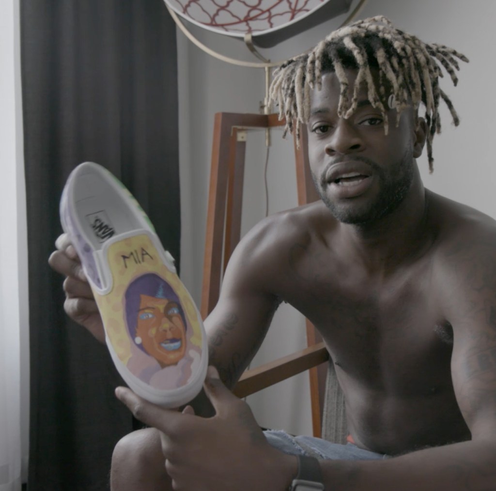 Image of NBA player Reggie Bullock holding a custom shoe with his sister's face printed on it.