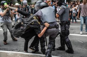 Policiais detendo um manifestante com truculência.