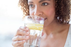 Vrouw met krullen drinkt citroenwater