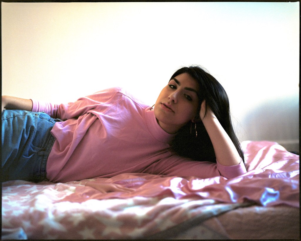 een foto van een trans vrouw met roze shirt op bed