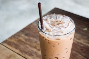 glass of iced coffee with a straw on a wooden table