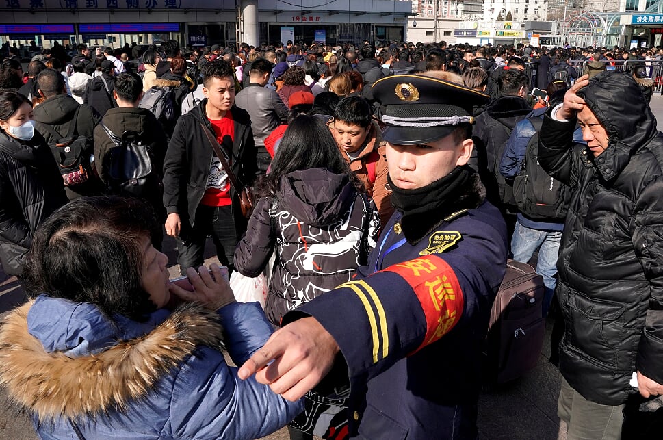 A security personnel guides passengers to enter a subway at Beijing Railway Station during the Chinese Lunar New Year travel rush in Beijing