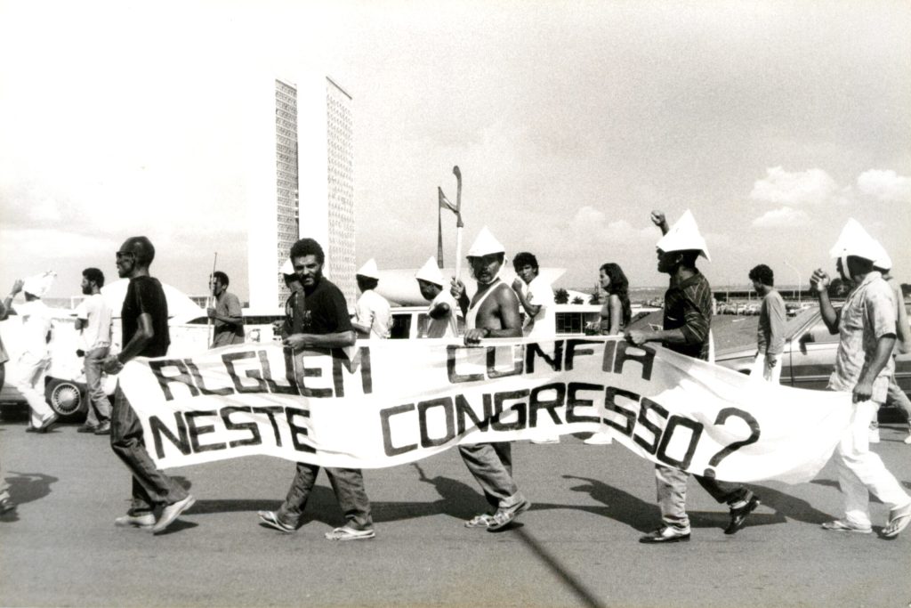 Homens no Congresso Nacional segurando faixa com os dizeres "Alguém confia neste Congresso?"