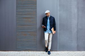 Slender man in stylish clothing standing against a wall.