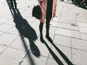 Woman standing with a person behind her lurking in the shadows