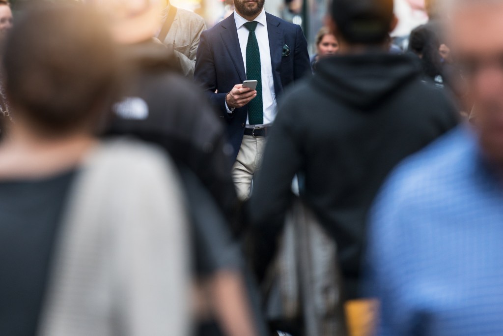 Man with a phone in a crowd.