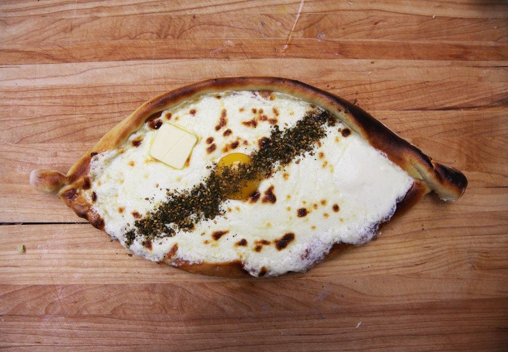 adjaruli khachapuri topped with butter, egg yolk, and za'atar